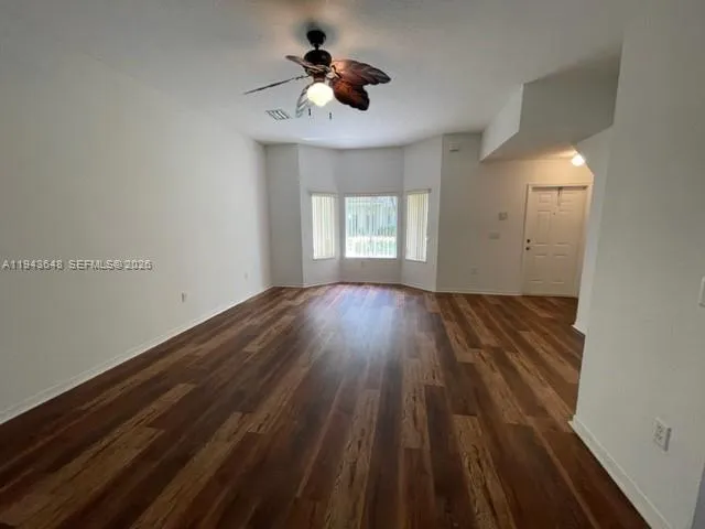 a view of wooden floor and a chandelier fan in a room