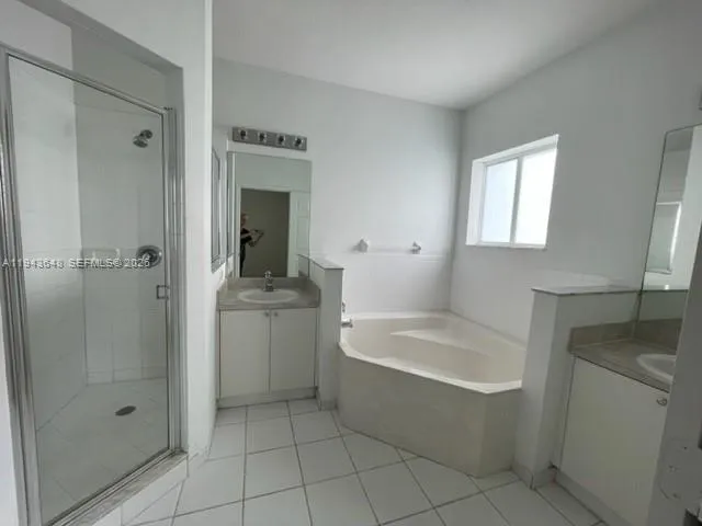 a bathroom with a bathtub a sink a window and a shower