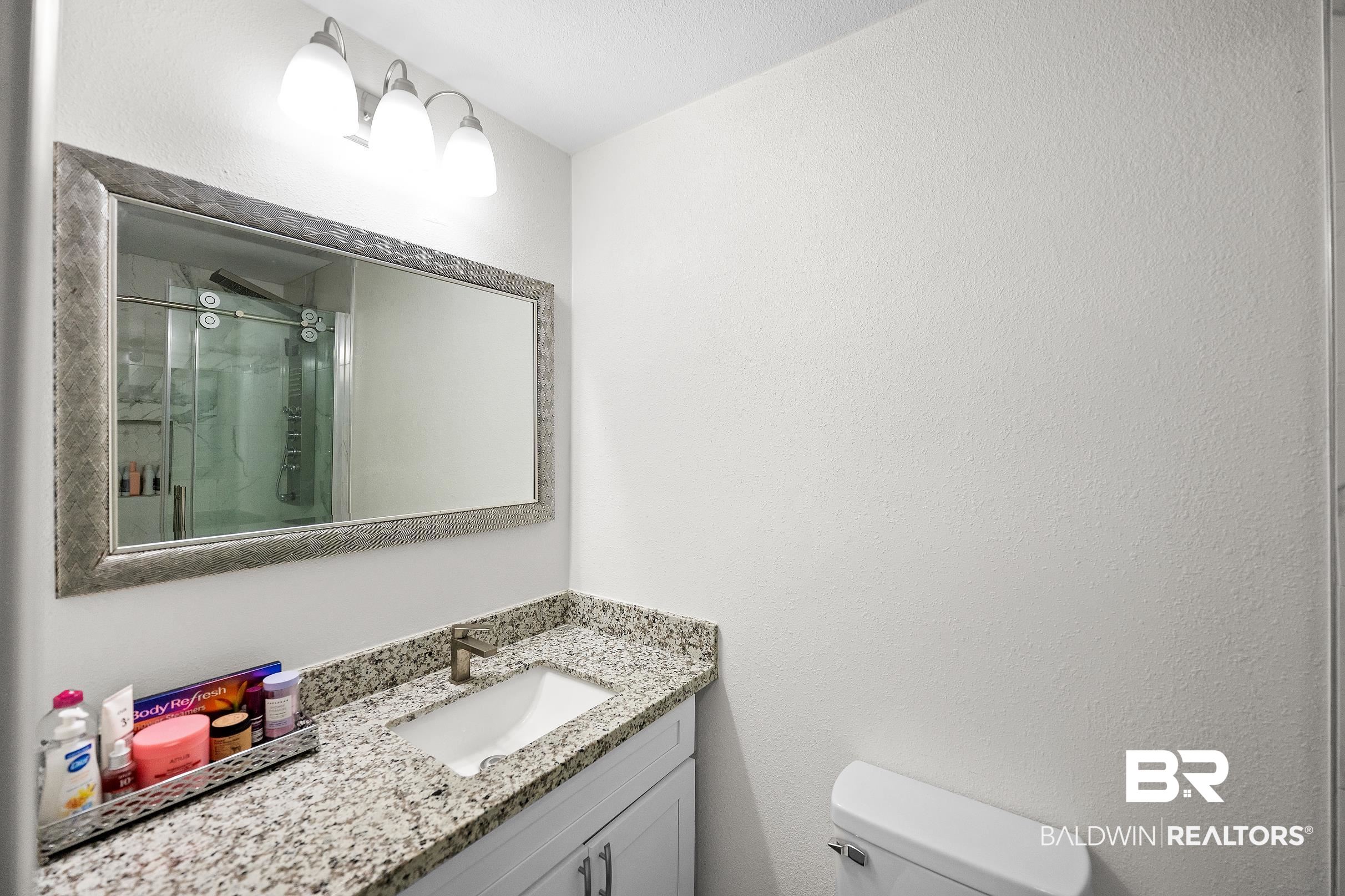 33129 Antietam Road Lillian, AL 36549 - Photo 15 of 31 Bathroom vanity featuring a granite countertop, integrated sink, and brushed nickel faucet