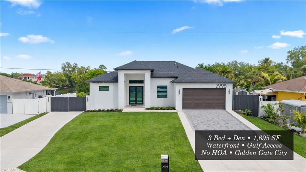 View of front of house with stucco siding, a gate, driveway, and an attached garage