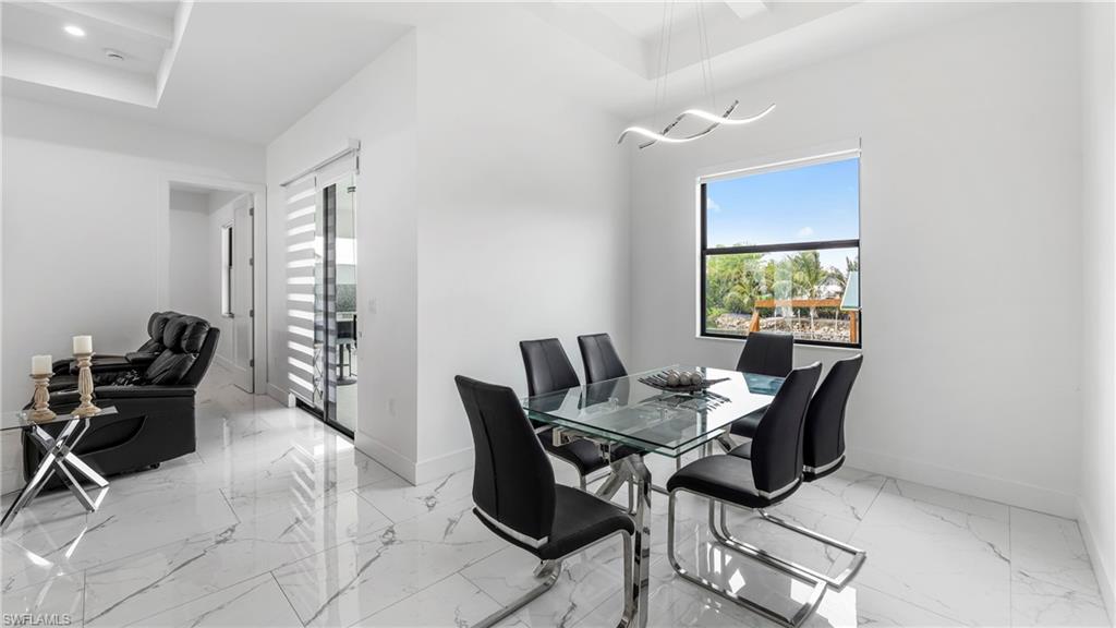 2998 52nd Street Southwest Naples, FL 34116 - Photo 10 of 44 Dining space featuring light marble finish flooring and a tray ceiling