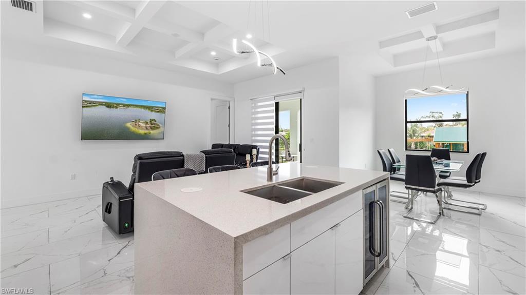 2998 52nd Street Southwest Naples, FL 34116 - Photo 44 of 44 Kitchen featuring coffered ceiling, a kitchen island with sink, open floor plan, light stone countertops, and plenty of natural light