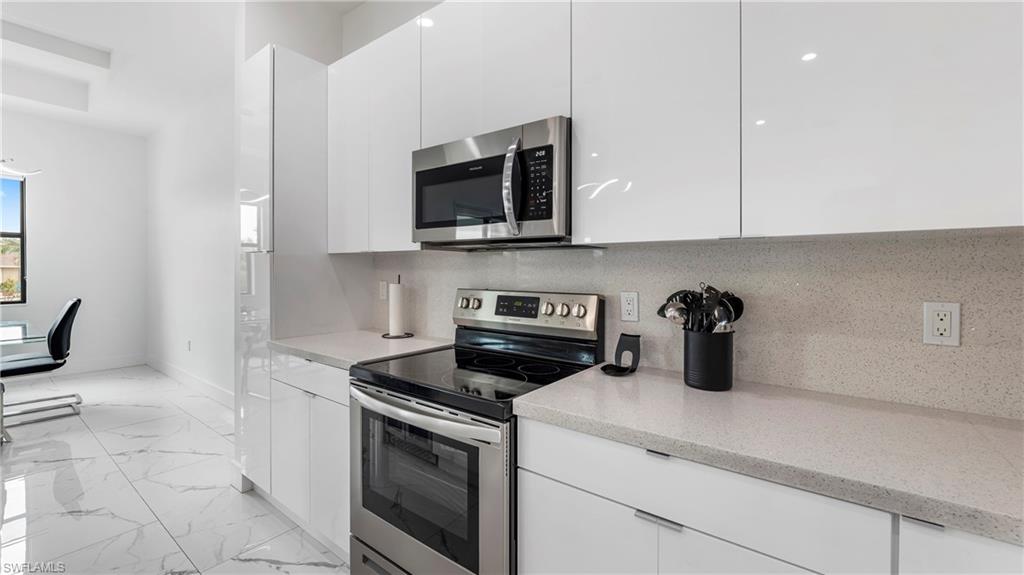 2998 52nd Street Southwest Naples, FL 34116 - Photo 13 of 44 Kitchen featuring stainless steel appliances, white cabinets, modern cabinets, and light marble finish floors