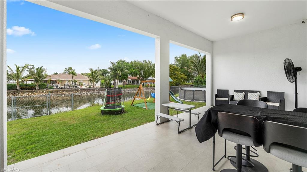 2998 52nd Street Southwest Naples, FL 34116 - Photo 32 of 44 Fenced backyard with a patio, outdoor dining space, a playground, a trampoline, and a water view