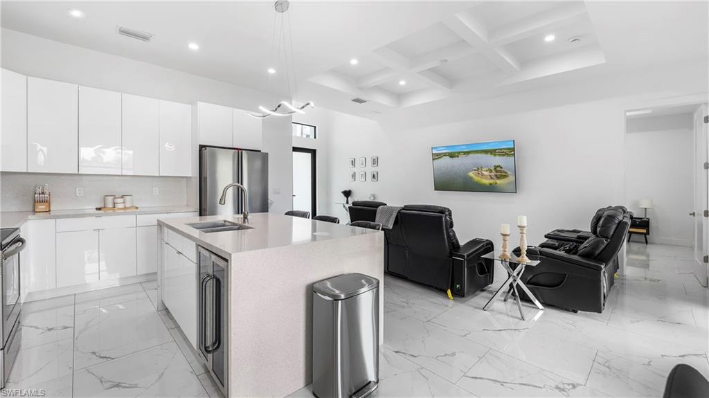 2998 52nd Street Southwest Naples, FL 34116 - Photo 43 of 44 Kitchen with open floor plan, coffered ceiling, an island with sink, beverage cooler, and stainless steel appliances