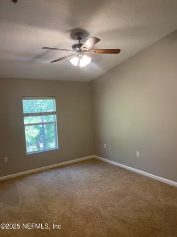 en empty room with windows and chandelier fan