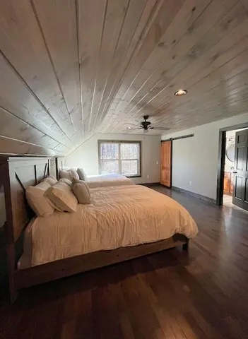 a spacious bedroom with a bed and wooden floor