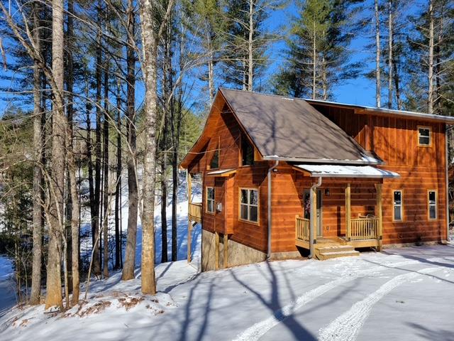 331 Vineyard Creek Way Murphy, NC 28906 - Photo 43 of 43 a view of a white house with large windows and a table and chairs under an umbrella