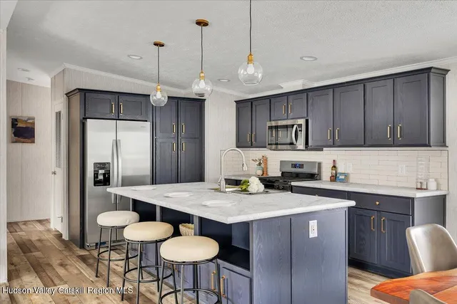 a kitchen with stainless steel appliances granite countertop a sink a stove a refrigerator cabinets and chairs