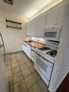 a kitchen with granite countertop a stove a sink and a refrigerator
