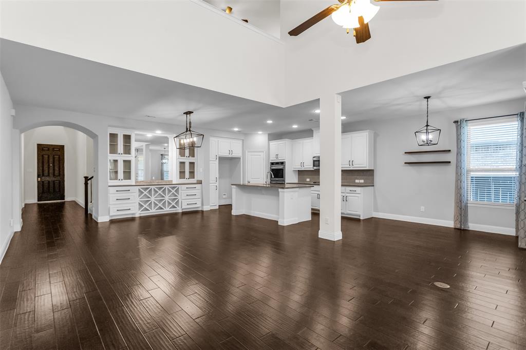 15713 Canyon Ridge Prosper, TX 75078 - Photo 14 of 38 Expansive open-concept living space featuring high ceilings, dark wood-finish flooring, and a built-in cabinetry unit with glass display doors