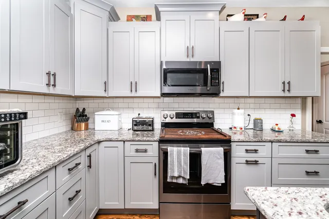 a kitchen with stainless steel appliances granite countertop a stove a sink dishwasher and a refrigerator with wooden cabinets