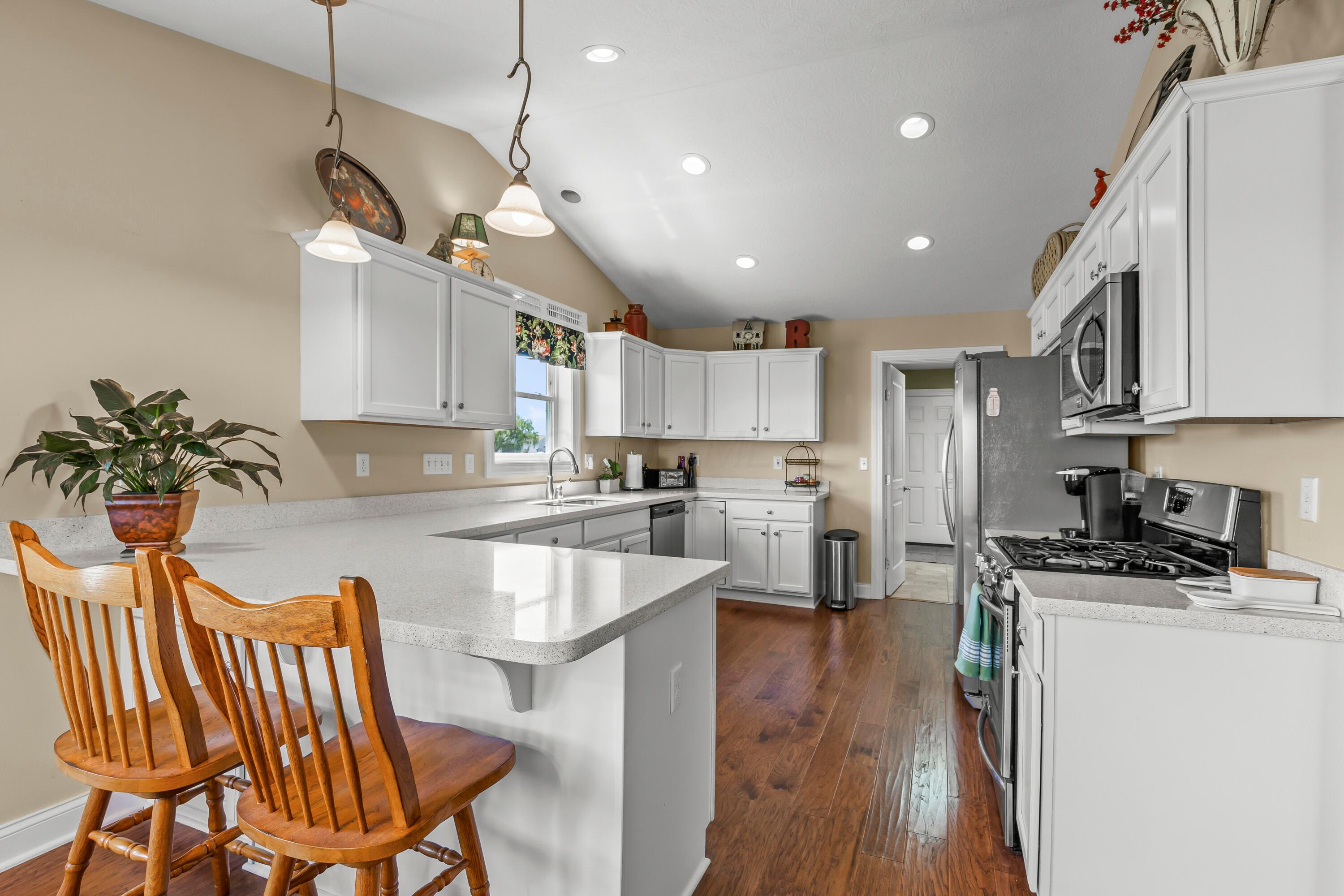 3582 Panhandle Road Delaware, OH 43015 - Photo 25 of 65 • New englewood flooring ~ 2015 • Ivory painted walls • Cathedral ceiling • New quartz countertops ~ 2015 • Can lighting • White cabinets • Double bowl, stainless steel sink with sprayer • Frigidaire® dishwasher • New Frigidaire® refrigerator ~ 2024 • Frigidaire® microwave • Frigidaire® gas range • Breakfast bar ledge • Disposal • Pendant lights over Dinette • Electric outlet above cabinets