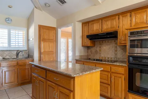 a kitchen with granite countertop a sink stove and cabinets