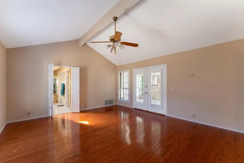 a view of an empty room with window and wooden floor
