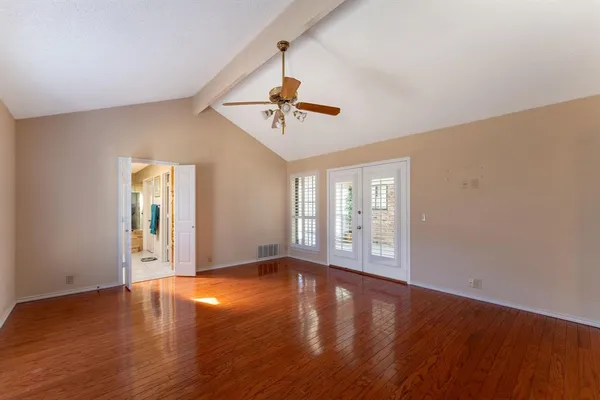 a view of an empty room with window and wooden floor