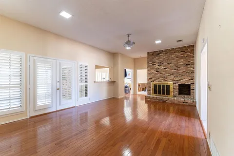 a view of a big room with wooden floor and windows