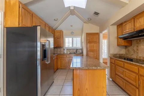 a kitchen with stainless steel appliances granite countertop a refrigerator a stove and a sink with cabinets