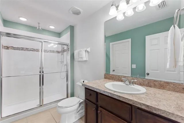 a bathroom with a granite countertop sink a toilet a mirror a vanity and shower