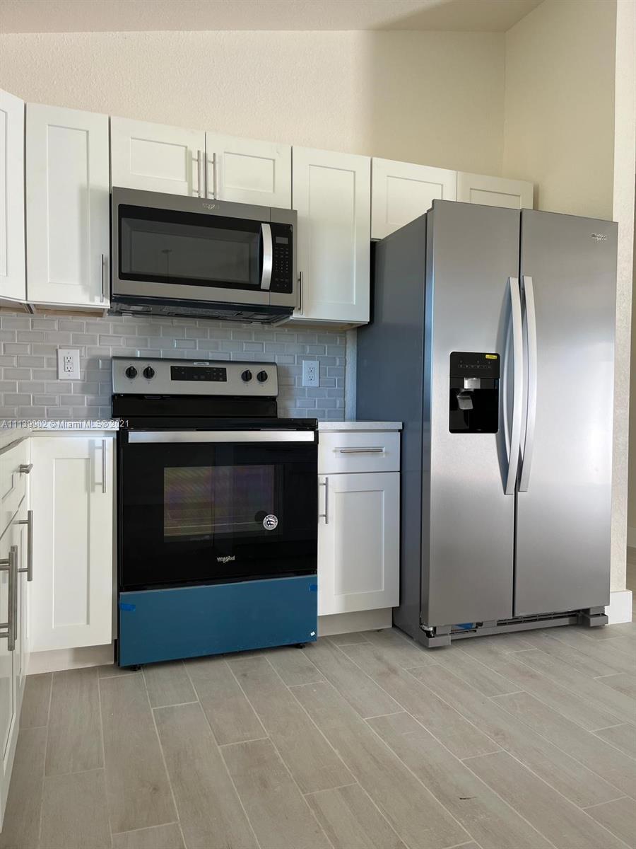 417 Cherry Tree Drive Sebring, FL 33876 - Photo 25 of 39 a kitchen with stainless steel appliances a stove a microwave and a hard wood floor