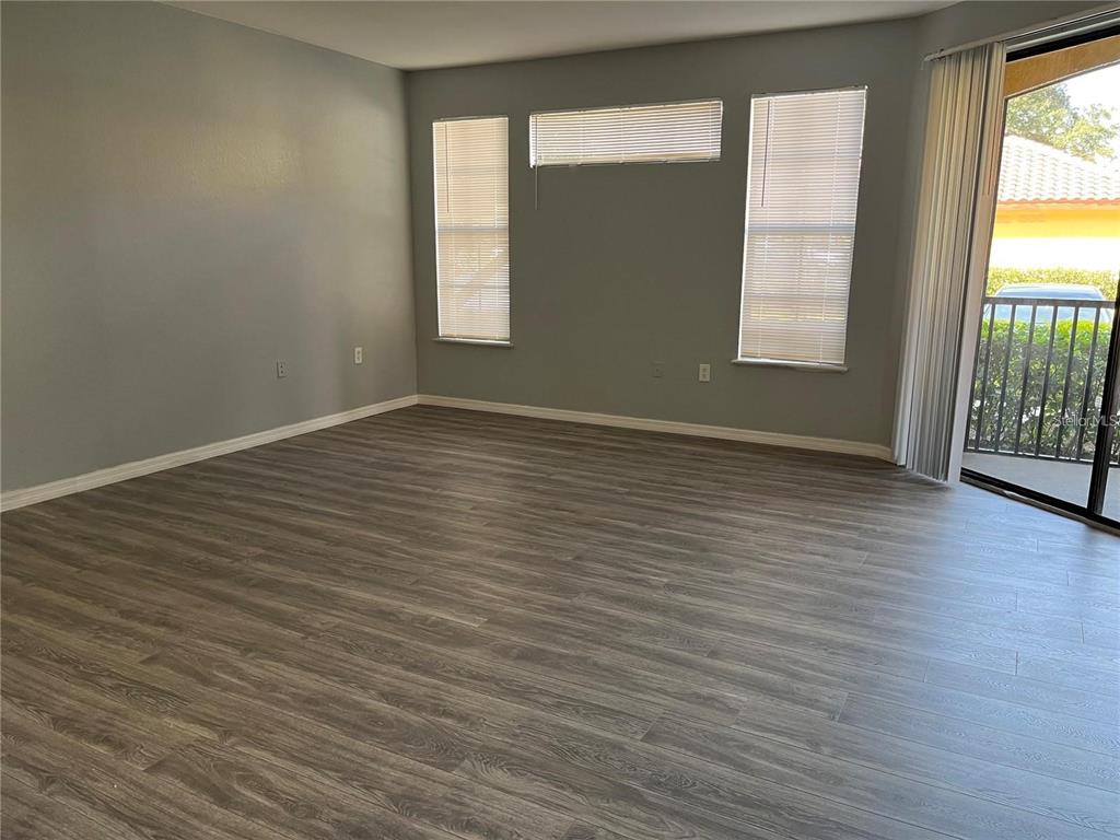 6157 Metrowest Boulevard, Unit 101 Orlando, FL 32835 - Photo 3 of 10 an empty room with wooden floor and windows