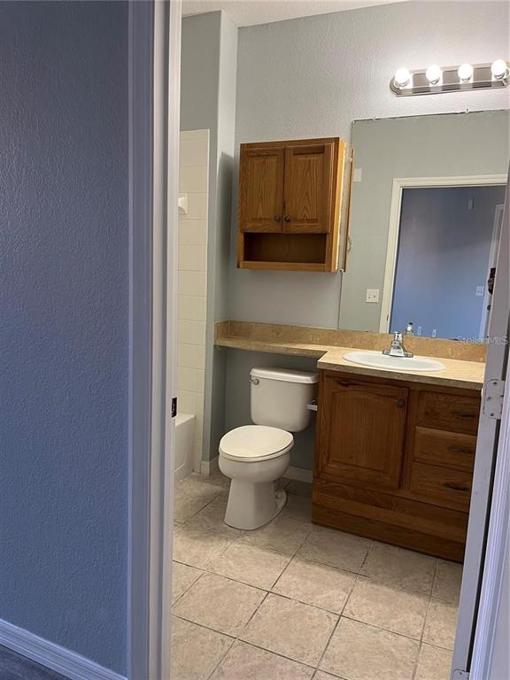 6157 Metrowest Boulevard, Unit 101 Orlando, FL 32835 - Photo 4 of 10 a bathroom with a toilet a sink and mirror