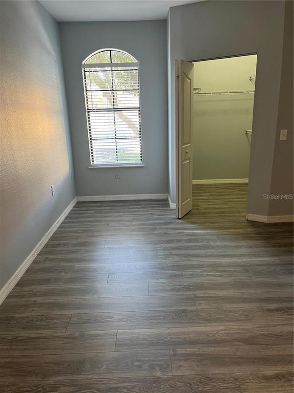 6157 Metrowest Boulevard, Unit 101 Orlando, FL 32835 - Photo 8 of 10 an empty room with wooden floor and windows