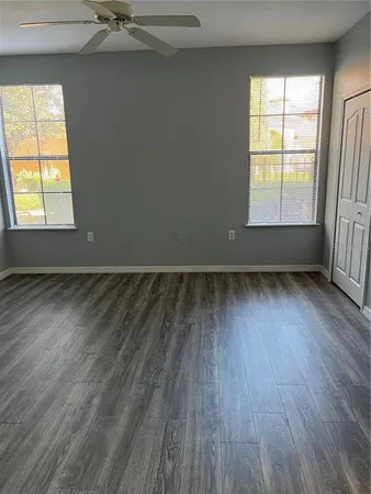an empty room with wooden floor and windows