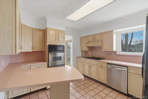 a kitchen with stainless steel appliances a sink a stove a refrigerator cabinets and a window