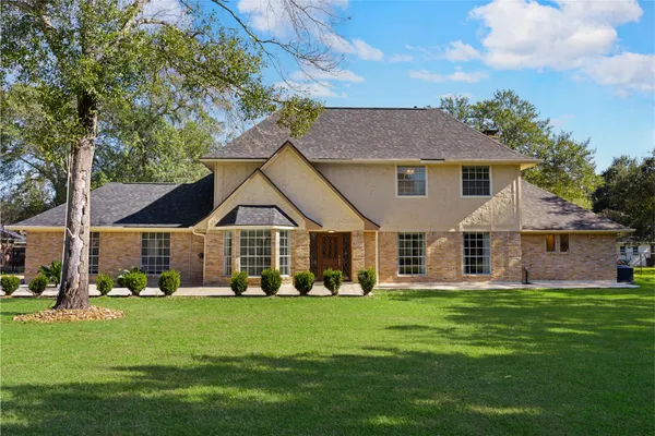 a front view of a house with a garden and trees