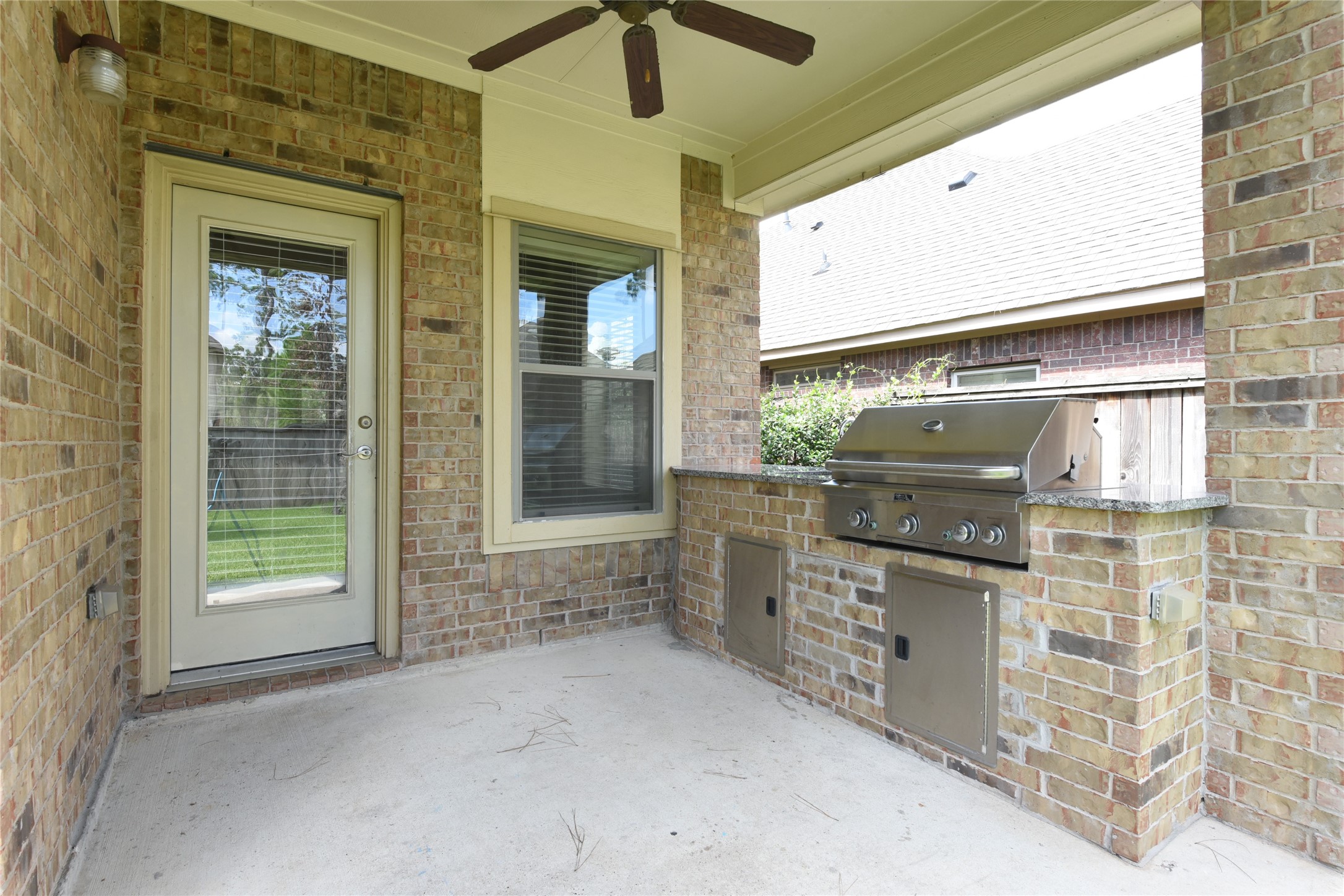 Charming covered patio with a built-in stainless steel grill, perfect for outdoor cooking and entertaining.