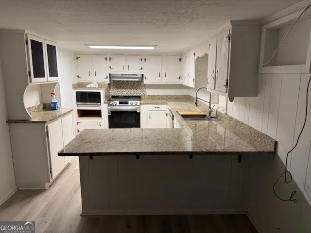 a kitchen with stainless steel appliances granite countertop a sink a stove a refrigerator and a cabinets