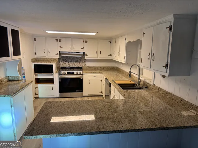 a kitchen with stainless steel appliances granite countertop a sink a stove and a refrigerator