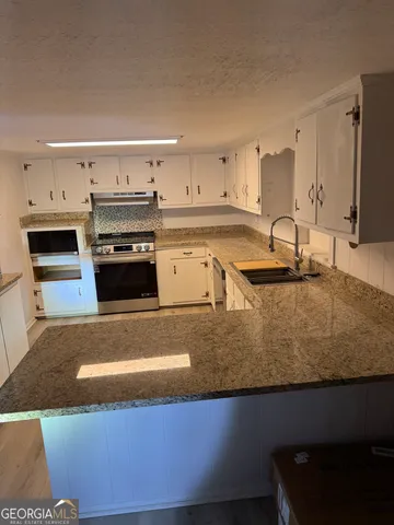 a kitchen with stainless steel appliances granite countertop a sink a stove and a refrigerator