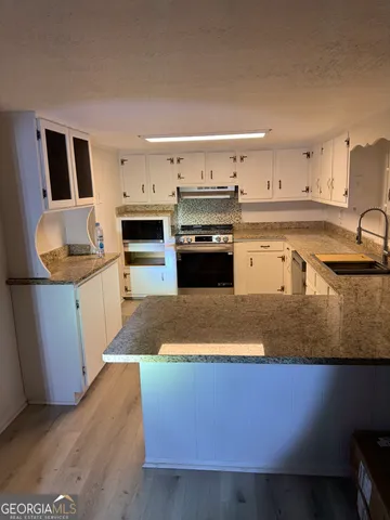 a kitchen with stainless steel appliances granite countertop a sink a stove top oven a chimney and a center island