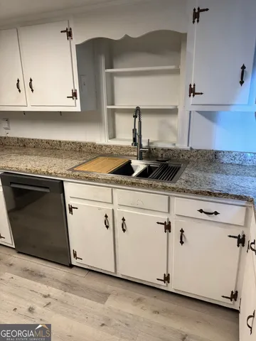 a kitchen with granite countertop white cabinets and a stove