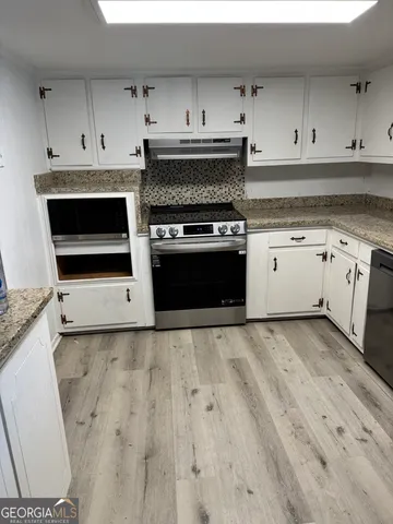 a kitchen with granite countertop white cabinets and white appliances