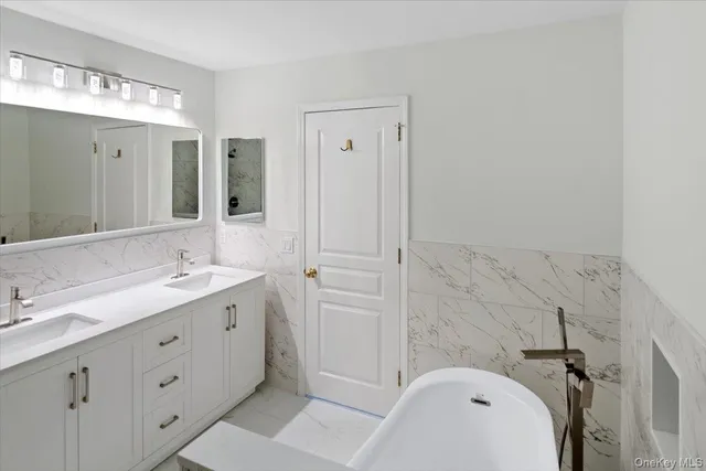 a bathroom with a double vanity sink toilet mirror and bathtub