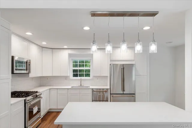 a kitchen with stainless steel appliances granite countertop a sink a stove and a refrigerator