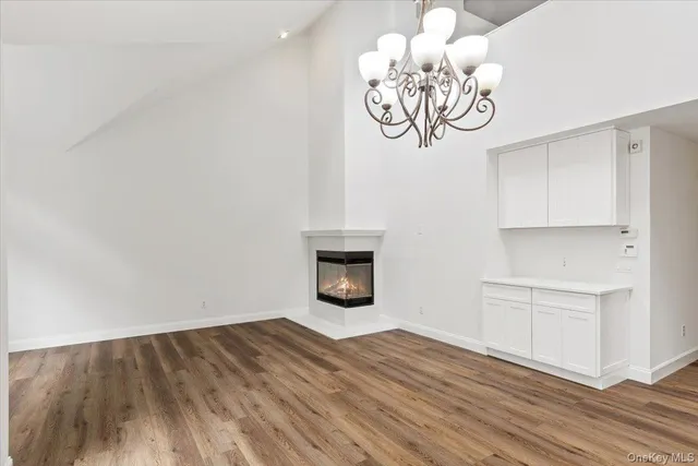 a view of empty room with wooden floor and kitchen