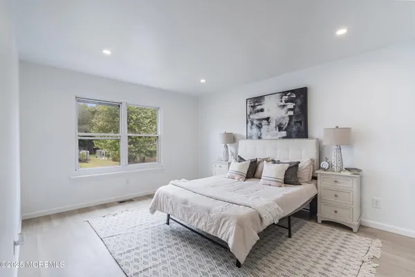 a spacious bedroom with a bed and a lamp on a dresser