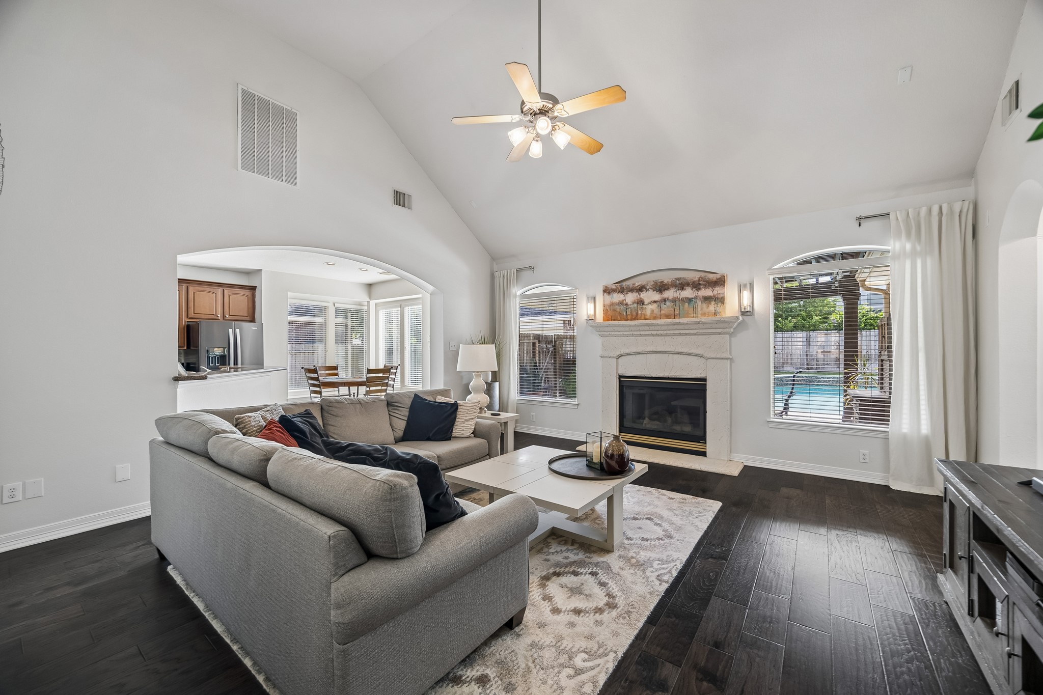 5718 Brennan Ridge Lane Katy, TX 77450 - Photo 8 of 42 OPEN CONCEPT LIVING WITH BACKYARD VIEWS: Soaring ceilings, a textured cast stone fireplace, and walls of windows create a bright, inviting gathering space with views of the private pool just beyond.