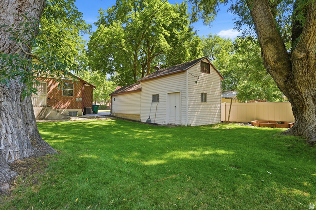 270 East 700 North Logan, UT 84321 - Photo 37 of 42 Expansive green lawn with mature trees and a detached outbuilding with a gambrel roof and vinyl siding