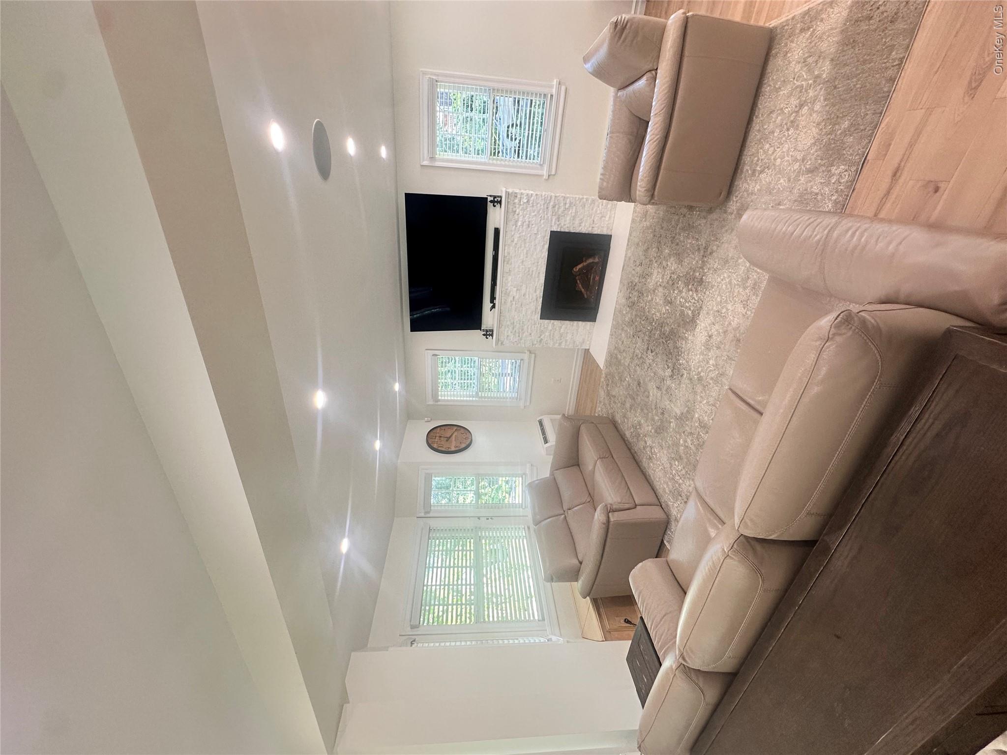 252 Beverly Road Queens, NY 11363 - Photo 6 of 19 Recessed lighting, wood-finish flooring, and a fireplace with a stone surround