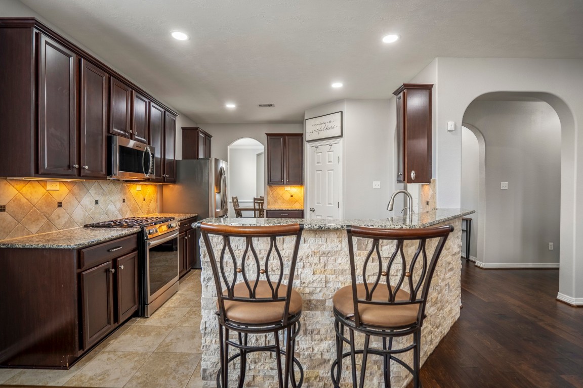27135 Cottage Stream Lane Fulshear, TX 77441 - Photo 12 of 42 Beautiful kitchen with a large island, bar seating and custom stone detail - perfect for cooking, gathering and entertaining.