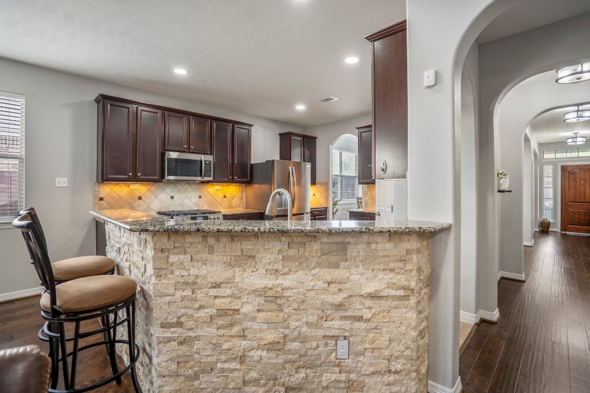 27135 Cottage Stream Lane Fulshear, TX 77441 - Photo 13 of 42 Stylish kitchen with granite countertops, custom stone island and bar seating, all flowing seamlessly into the main living areas.