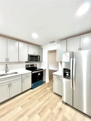 a kitchen with a refrigerator a sink and a stove top oven