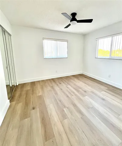a view of empty room with wooden floor and fan