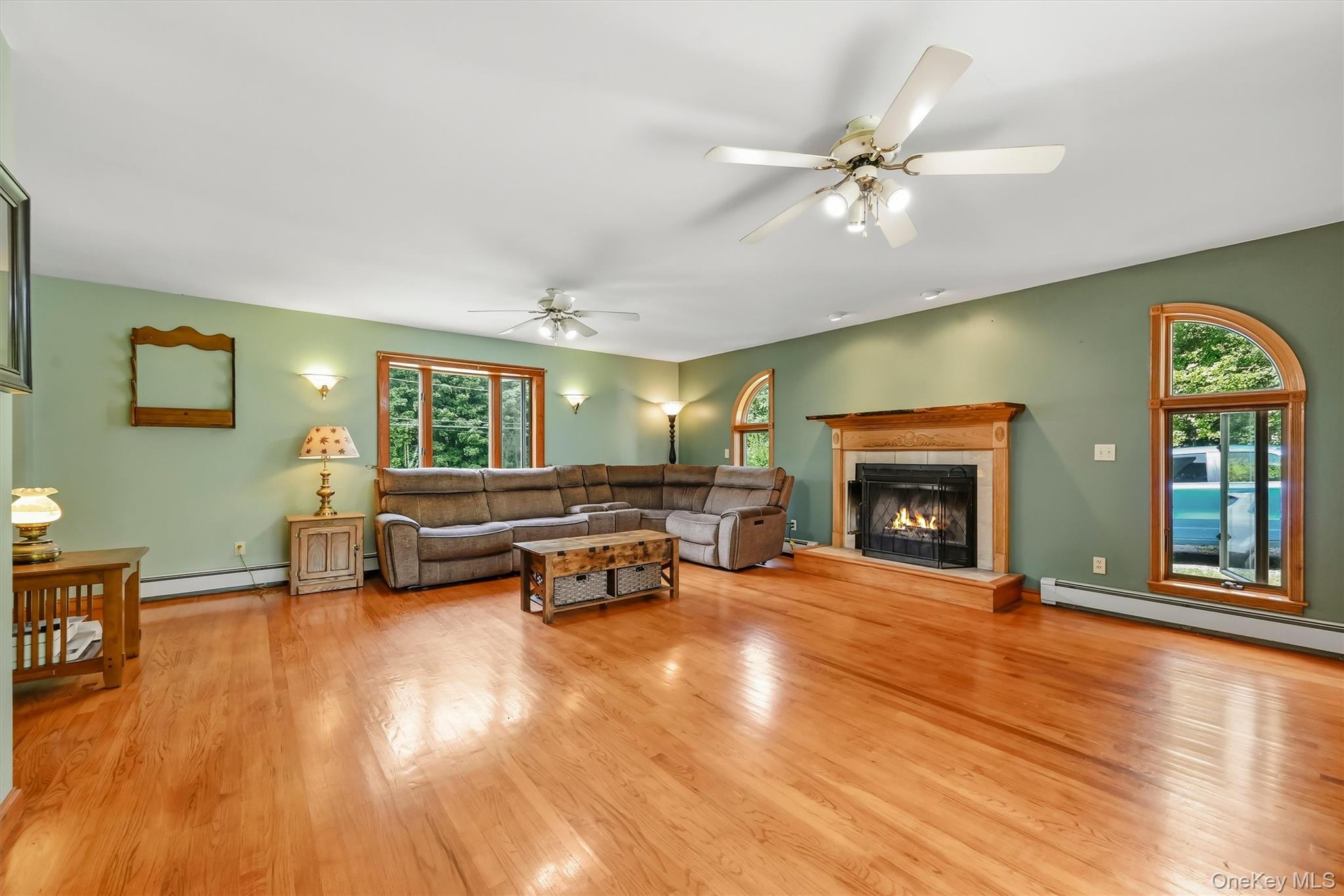 328 Big Island Road Florida, NY 10921 - Photo 8 of 40 Spacious family room featuring hardwood floors, a fireplace, and distinctive arched windows.