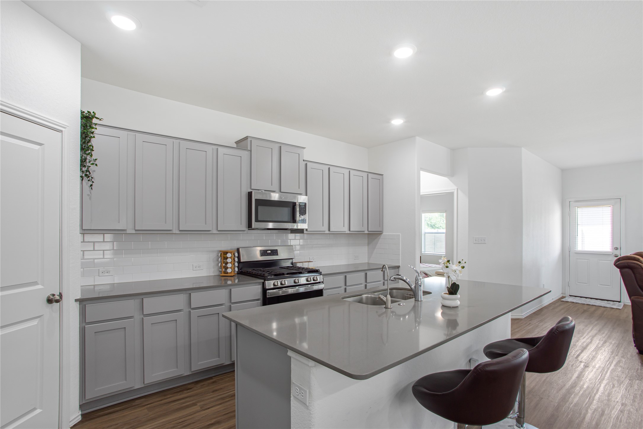 124 Cherry Ridge Road Georgetown, TX 78628 - Photo 12 of 23 Kitchen featuring gray shaker-style cabinetry, stainless steel appliances, subway tile backsplash, and wood-finish flooring